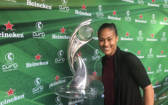 Rachel Yankey smiles next to the UEFA Women's Euro 2022 trophy.