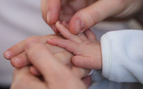 parent holding a baby's hand