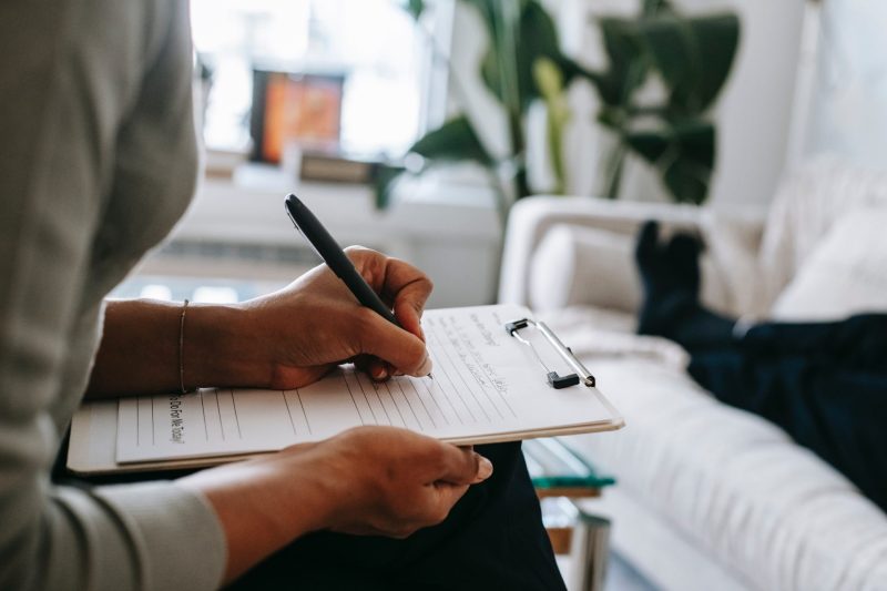 Psychologist writing on clipboard during session