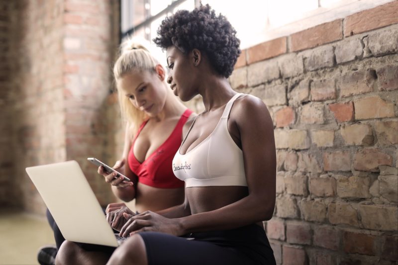 two women in fitness gear on a laptop