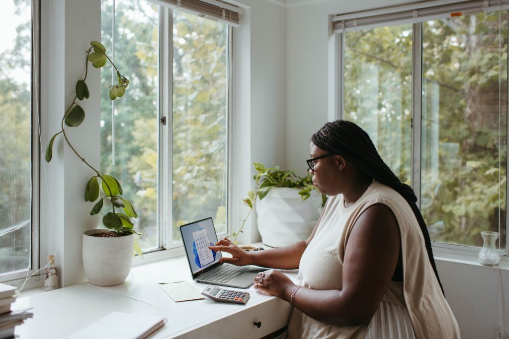 A woman sat at a desk writing on her laptop