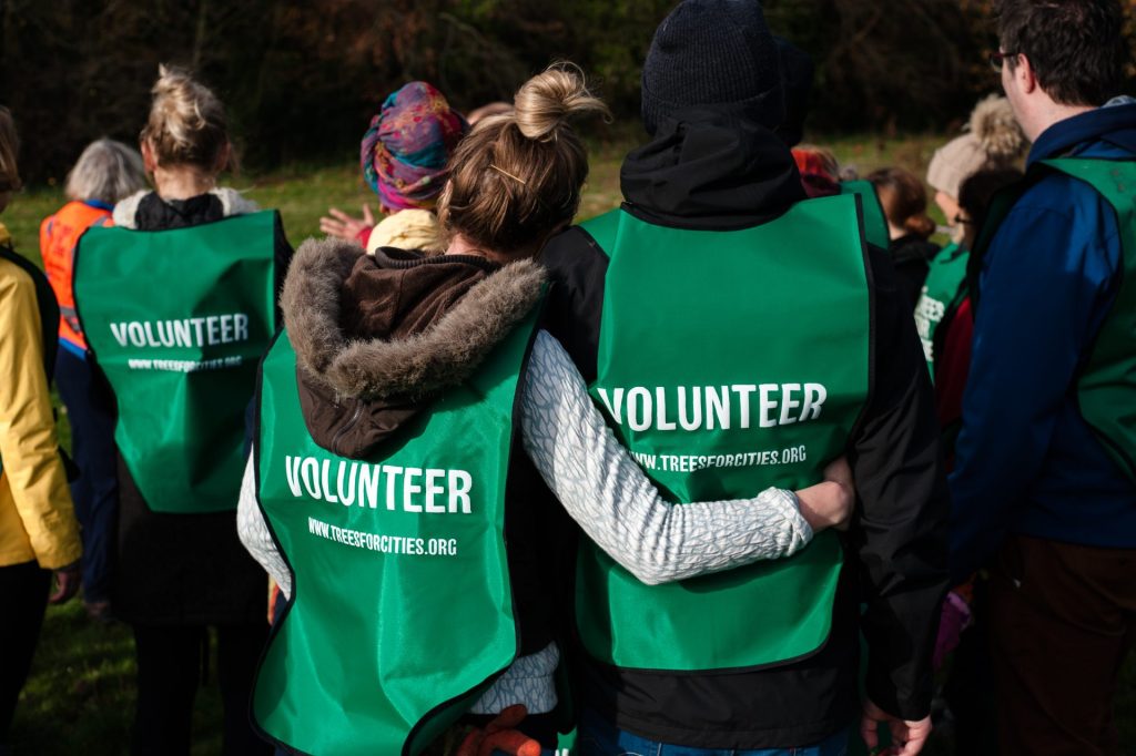 Tree-planting volunteers stand arm in arm.