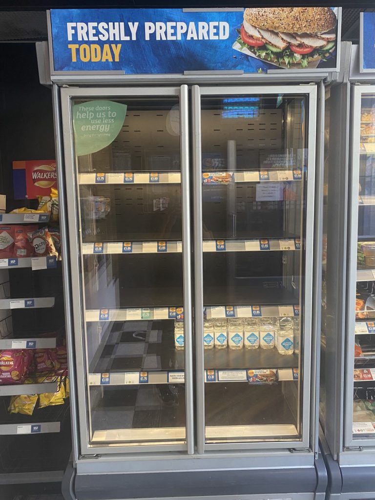 A Greggs fridge which usually holds drinks is empty and only has a few water bottles.
