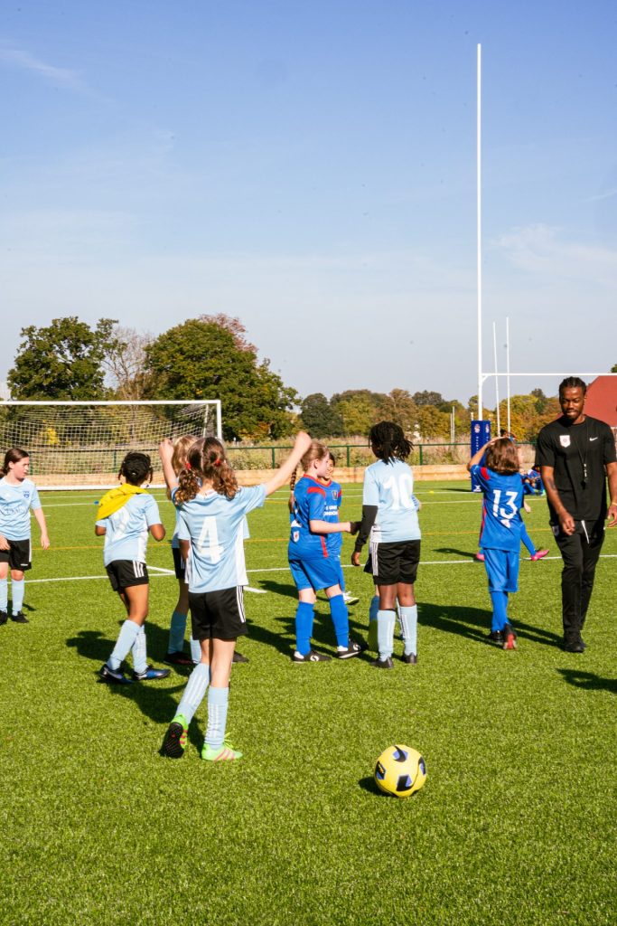 The two girls teams standing in the middle of a perfect football pitch