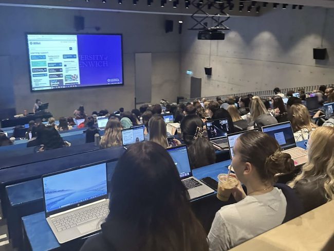 Crowded Greenwich university lecture students having to sit on the ground with no desk as they have nowhere to sit.