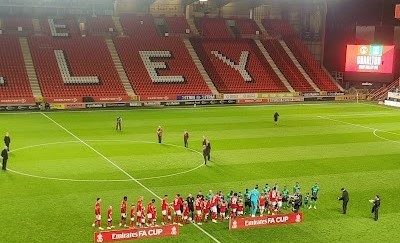 A photo of the two teams shaking hands on the pitch before the match.