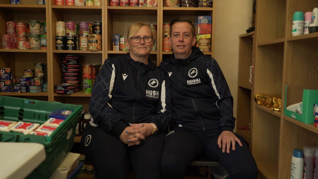 Kelly and Ellen Webster sitting newar shelves with food cans.