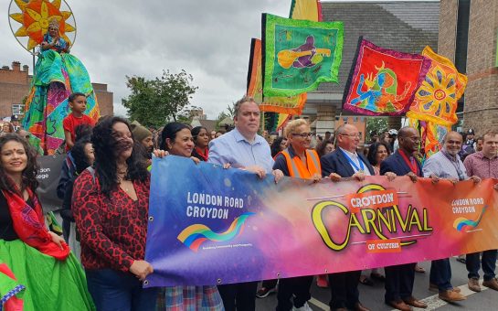 Croydon Carnival parade of banner with Mayors, and members of the public walking in front of the parade floats.