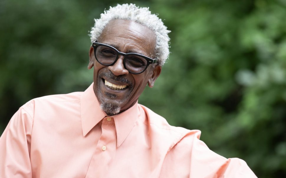 head and shoulders photos of soul singer Junior Giscombe, wearing a salmon coloured shirt.