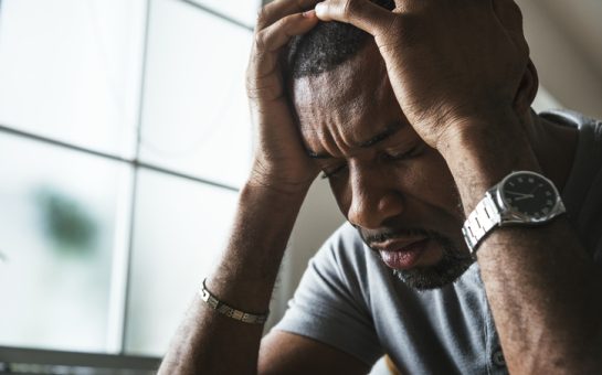 Black man in a stressed state with his head in his hands
