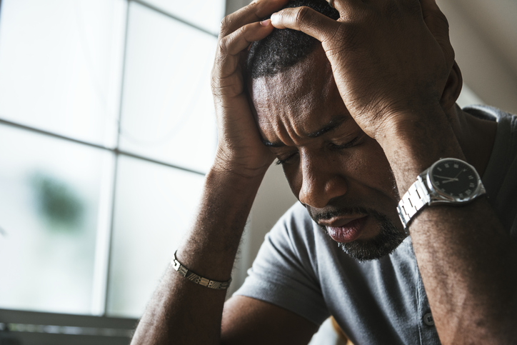 Black man in a stressed state with his head in his hands