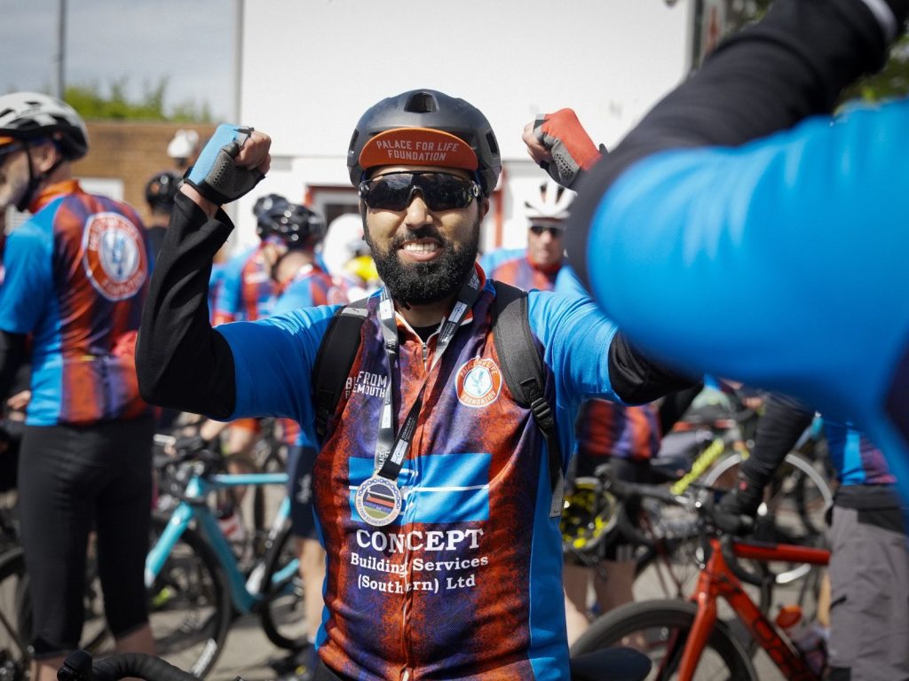 Male rider celebrates finishing Bike from Bournemouth 120-mile bike ride - wearing Bike from Bournemouth cycle jersey and medal