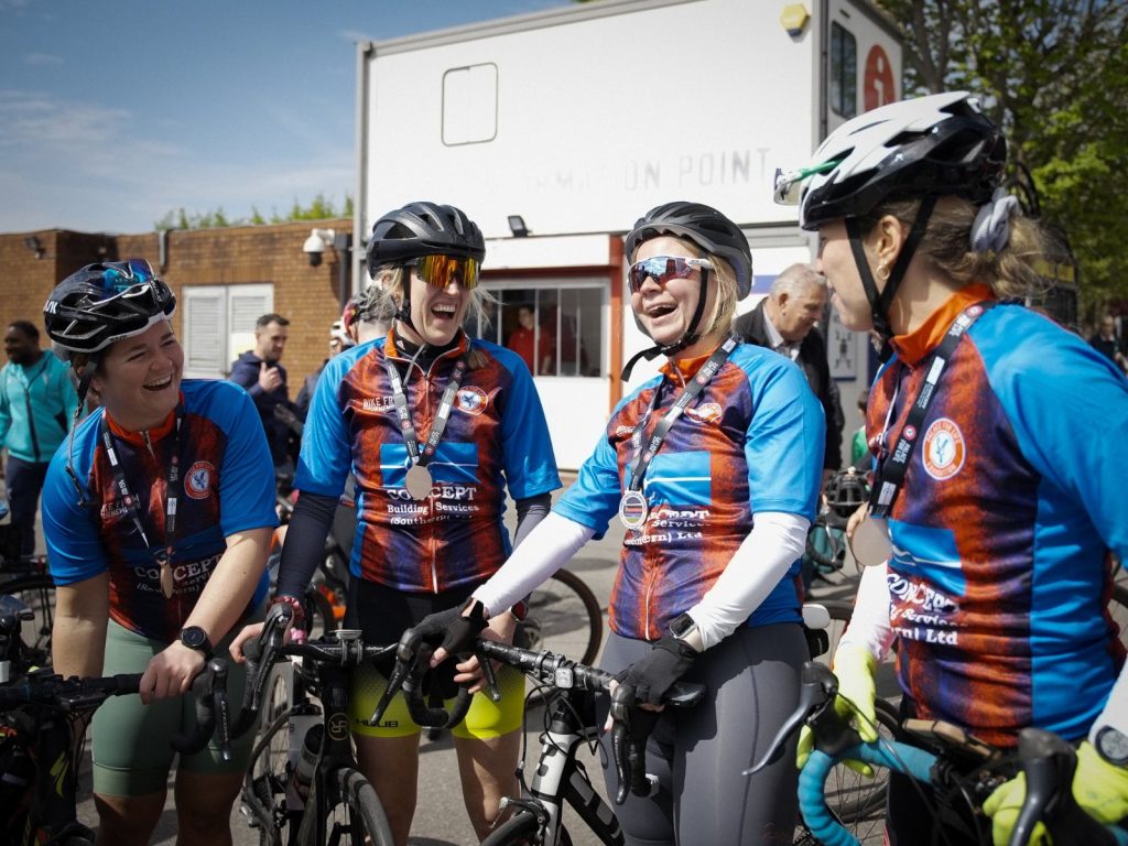 Four ladies laughing and celebrating finishing their Bike from Bournemouth charity ride