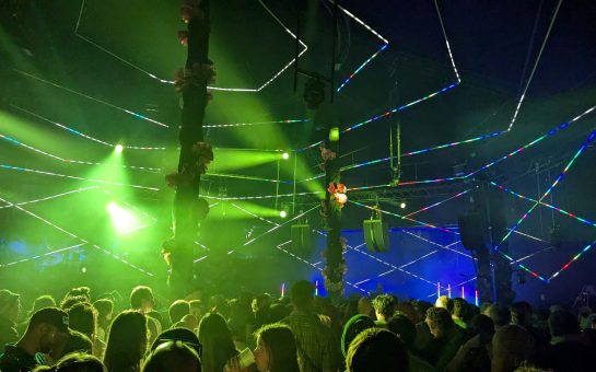 Green and blue lights spotlights over a crowd at a festival