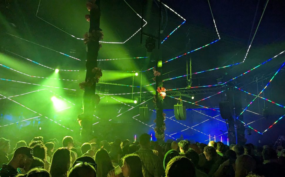 Green and blue lights spotlights over a crowd at a festival