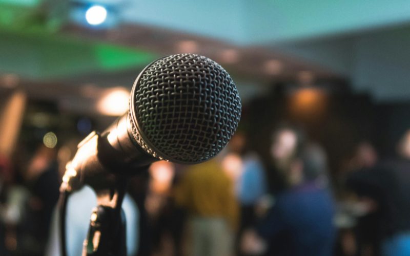 A photo of a microphone in front of a crowd.