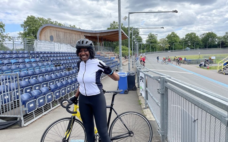 Bike Project recipient Aurore Longue stands proudly with her bike in her cycling lycra next to the track.