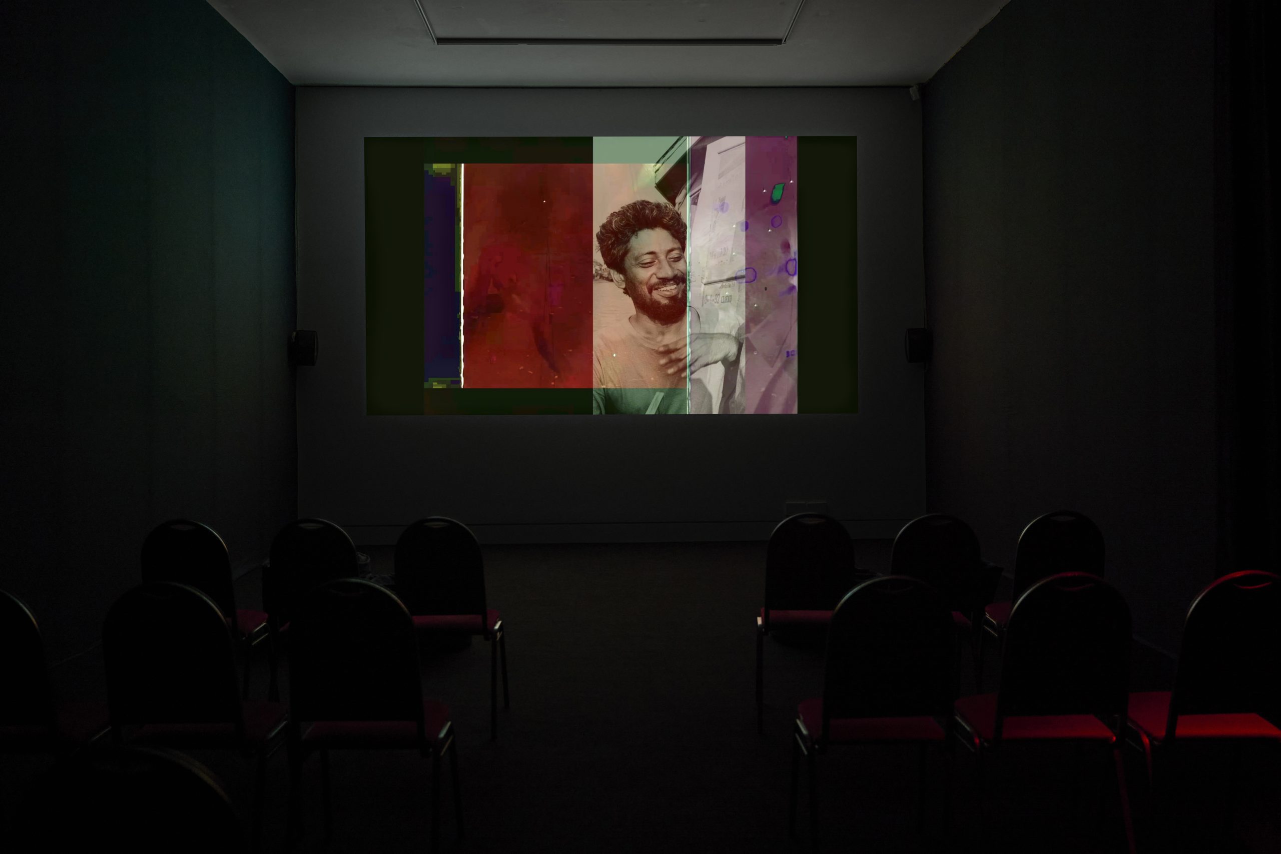 A cinema screening with a similing man on screen from Babu Eshwar Prasad's film, Dear Chalam, (2024).