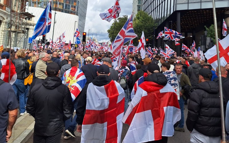 'Unite the Kingdom' protesters outside Waterloo station. Union Jack flags on their backs.