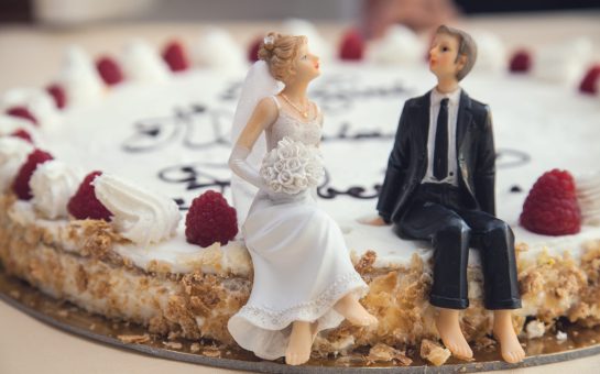 Model couple sat on top of wedding cake