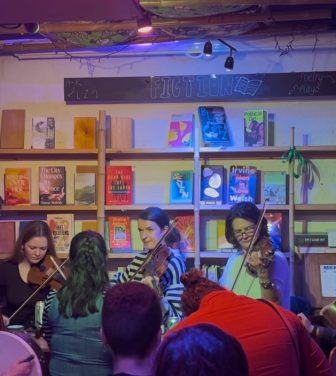 Photo: the bookshop, with the folk music night in full swing. Customers enjoying themselves in the foreground, musicians playing violins in the background