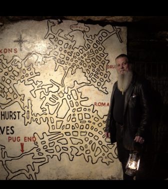 Cave manager Jason stands next to a map of the caves.