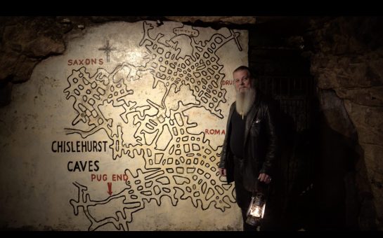 Cave manager Jason stands next to a map of the caves.
