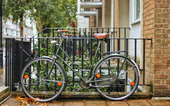 A green, classic bike is leaning on a fence at Hyde Park Crescent, London. (Credit: Free to use from Unsplash)
