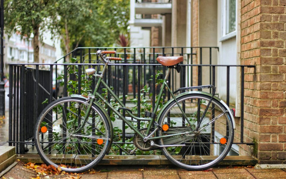 A green, classic bike is leaning on a fence at Hyde Park Crescent, London. (Credit: Free to use from Unsplash)