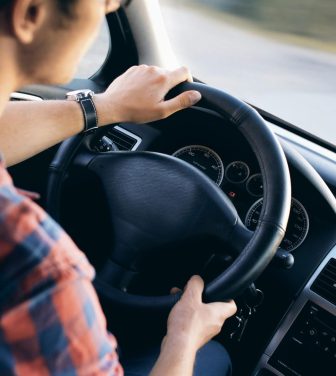 A young man sits at the steering wheel of a car