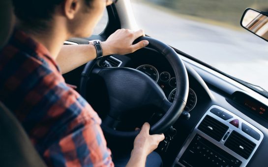 A young man sits at the steering wheel of a car