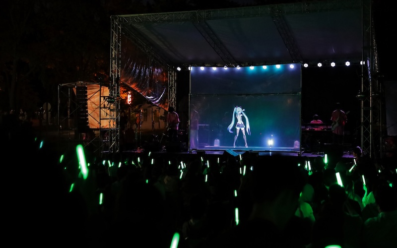 A group of vocaloid fans at a Hatsune Miku concert at Hokkaido University, holding up their light sticks.