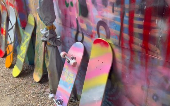 Graffiti painted skateboards lined up against wall.
