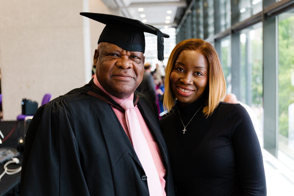 Chris Osagbaekhoe with his daughter, Uwa Oghagha. Chris is wearing a cap and gown for graduation; Uwa is a wearing a black dress.