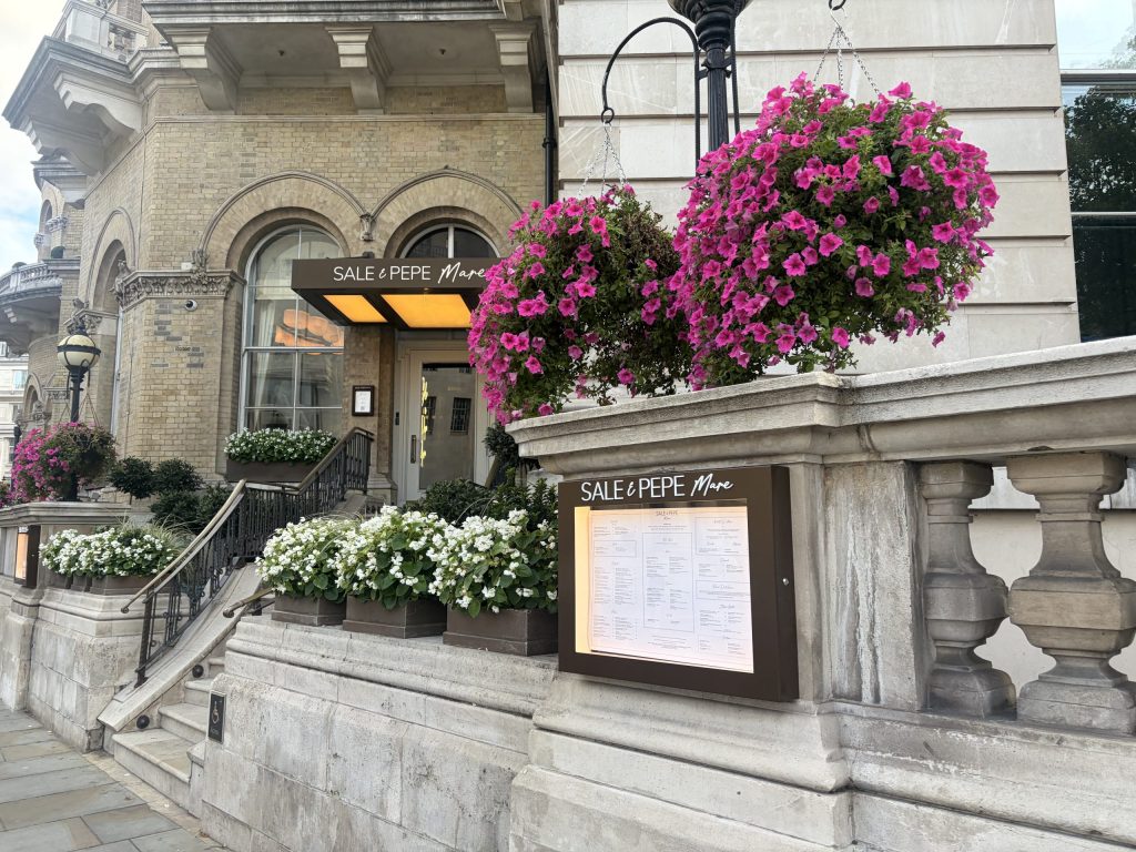Hanging baskets and flower planters decorating the entrance to Sale e Pepe Mare restaurant in the Langham Hotel, Marylebone.